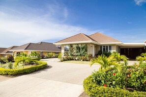 A residential area with multiple houses, paved driveways, and well-maintained gardens.