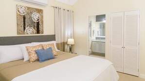 A hotel room with a bed, a nightstand, a lamp, a mirror, and a wardrobe. - Ocho Rios Villa Azul at Coolshade XIII (St. Ann's Bay)