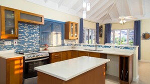 A modern kitchen with wooden cabinets, a built-in oven, and a large island. - Ocho Rios Villa Azul at Coolshade XIII (St. Ann's Bay)