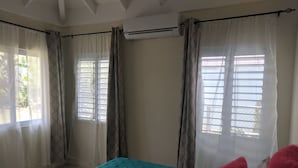 Ein Zimmer mit einem Bett, einem Vorhangfenster und einer Klimaanlage.