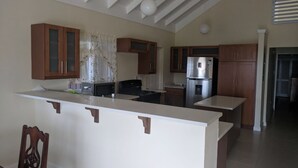 Eine moderne Küche mit Holzausstattung, einer zentralen Kochinsel und einem Edelstahlkühlschrank.