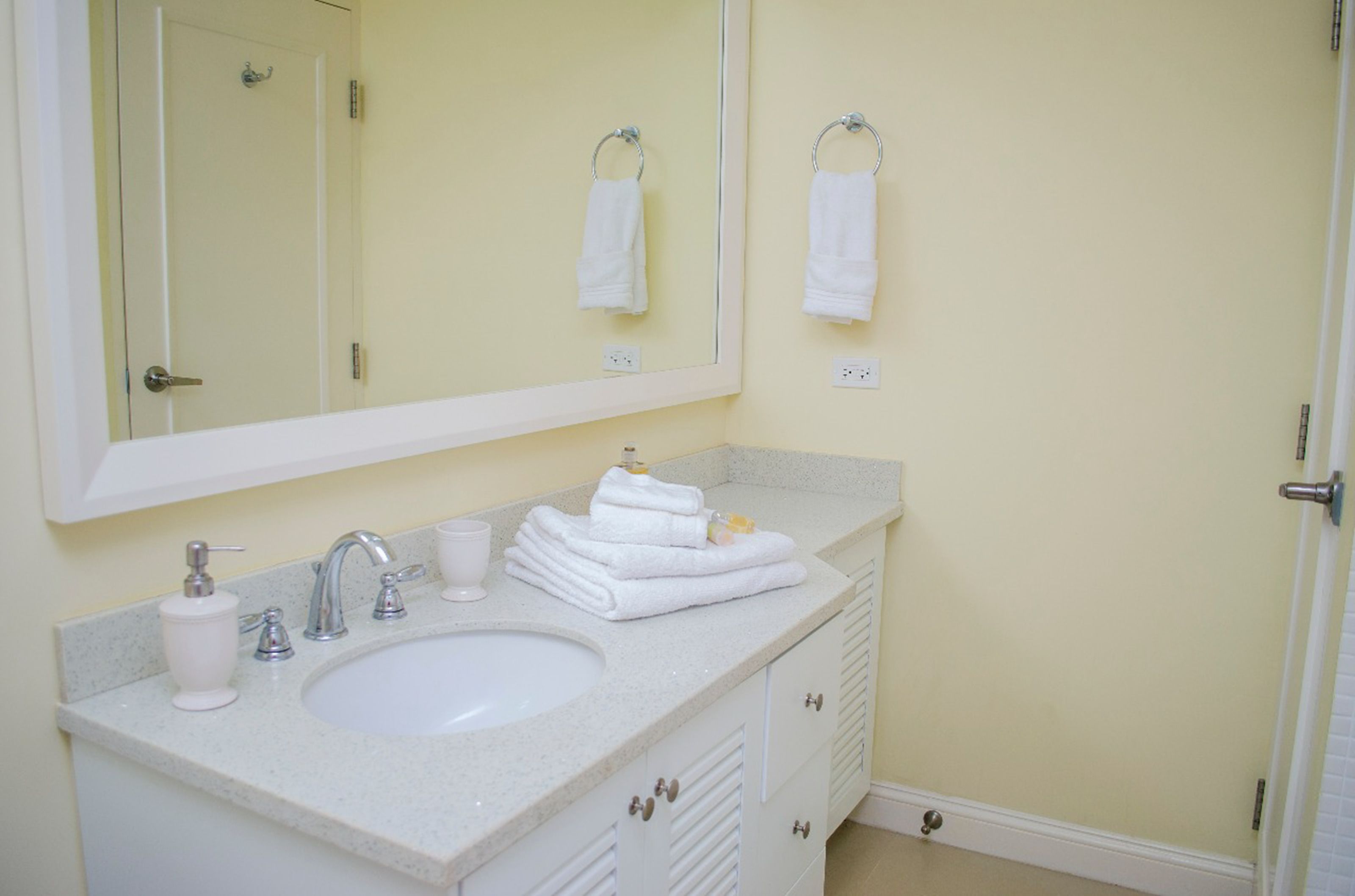 Un bagno con lavandino, specchio e asciugamani.