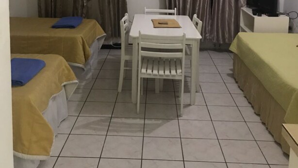 A hotel room with two single beds, a dining table, and a TV.