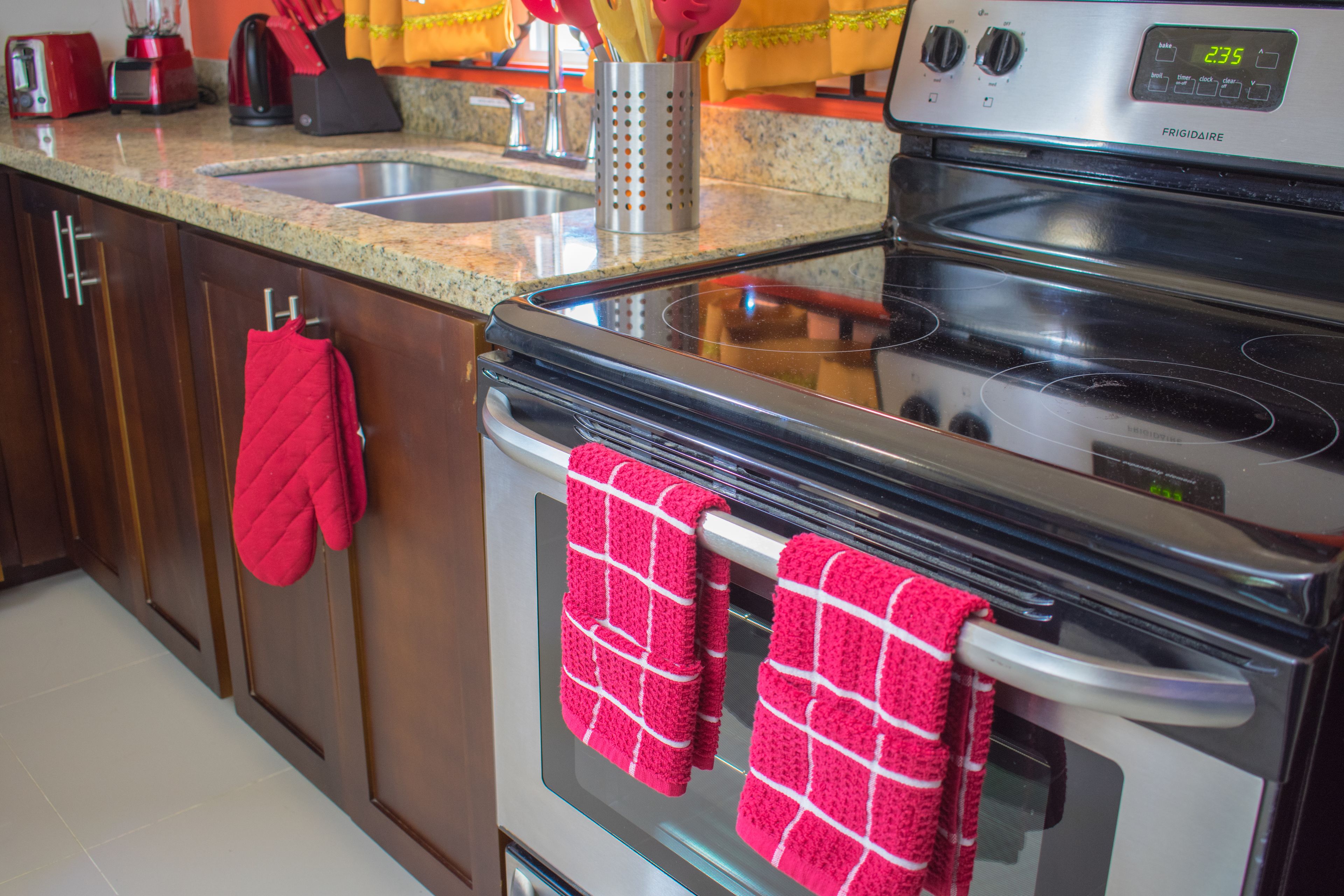 Una cocina con horno de acero inoxidable, encimera de granito y un guante de cocina rojo colgado en la puerta del horno.