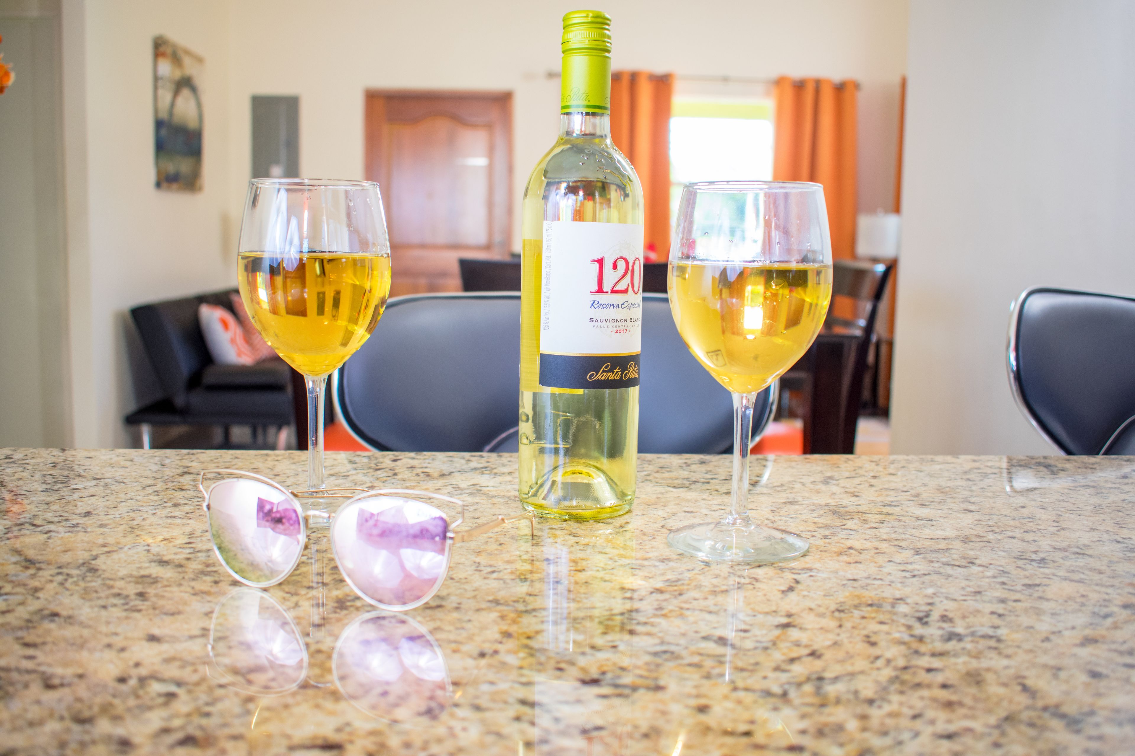 A bottle of wine and two glasses on a granite countertop.