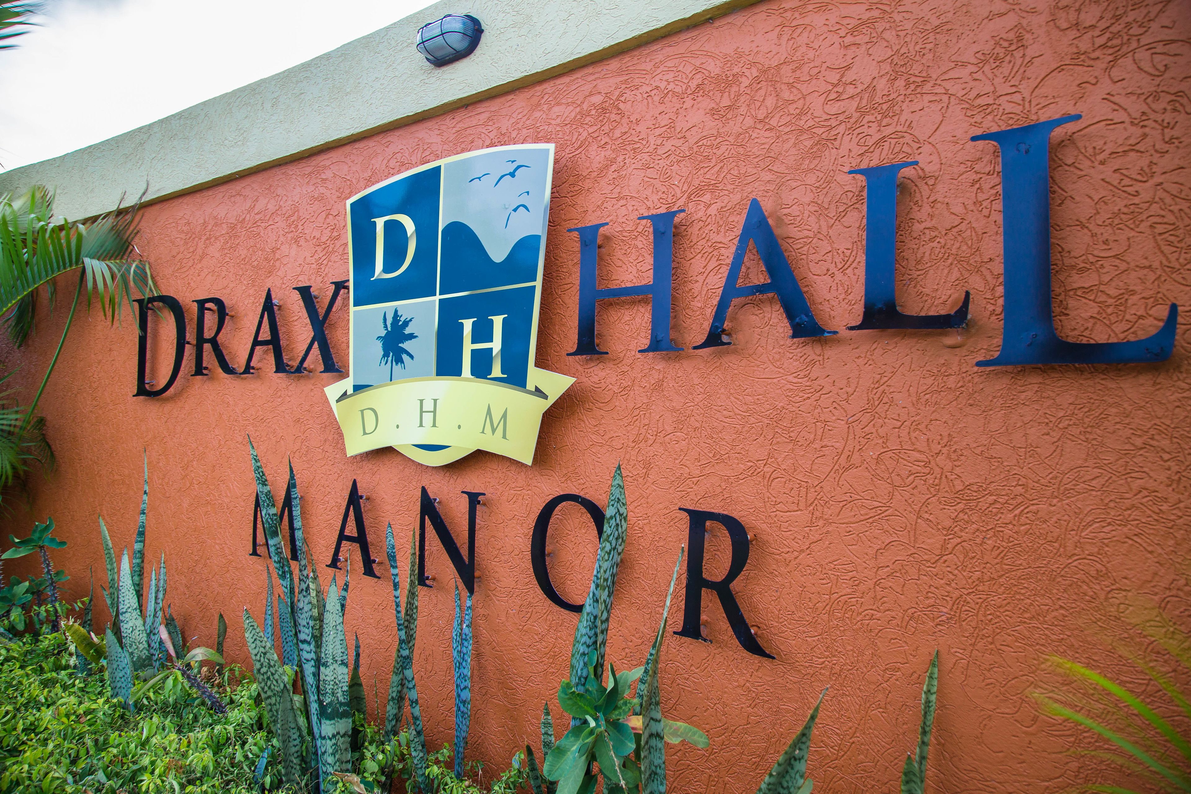 Een bord met de naam 'Drax Hall Manor' en een logo.