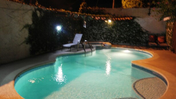 Een zwembad met een ligbed en een kleine jacuzzi.