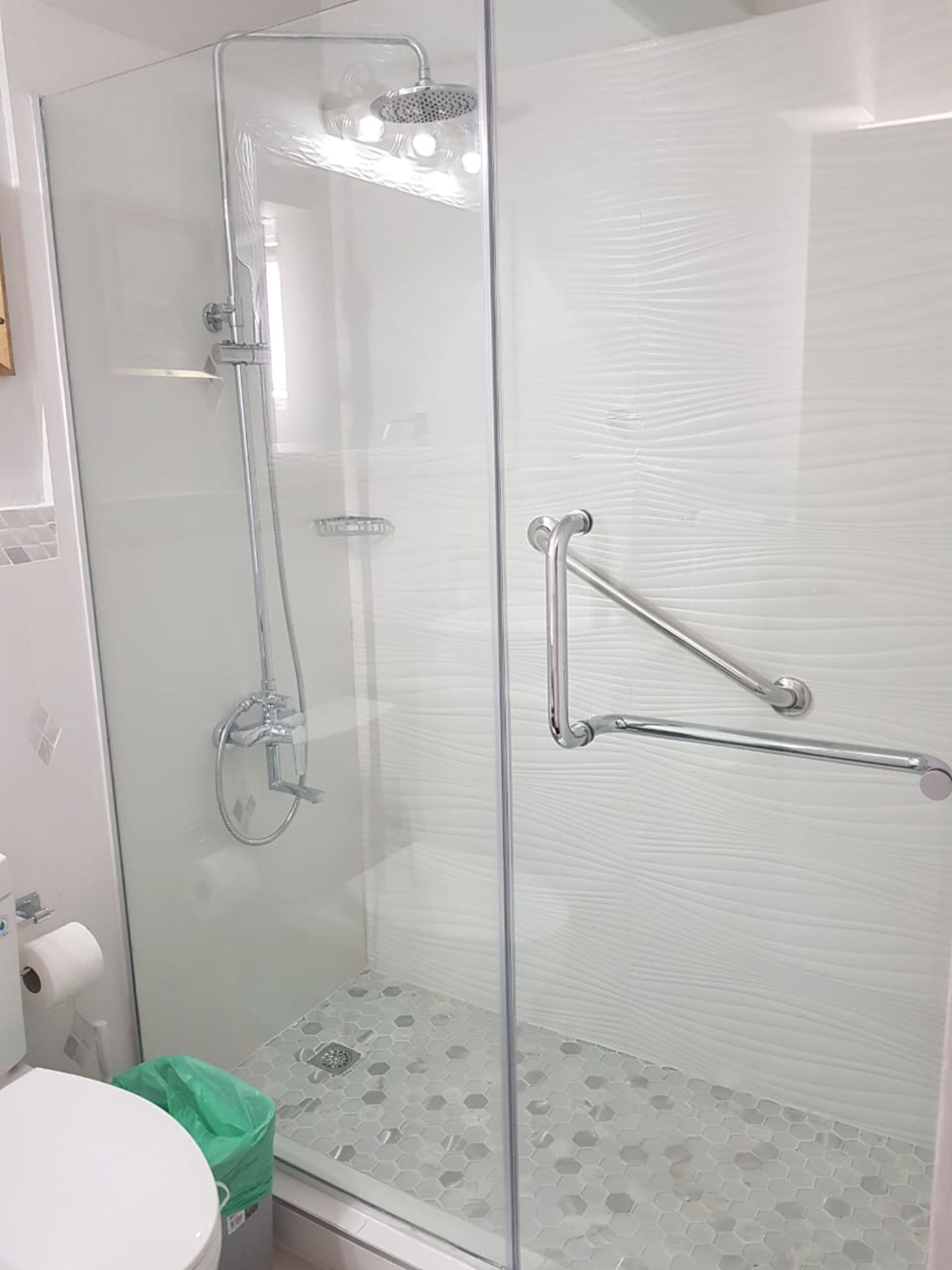 Een douche met glazen wanden, een handdouche en een extra sproeikop.