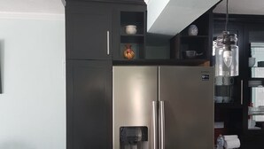 Uma cozinha moderna com geladeira de aço inoxidável, um dispenser de água e bancada de granito.