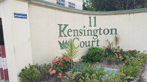 Placa indicando '11 Kensington Court', com um jardim na frente.
