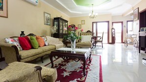 Un salón amplio con sofá, sillones, una mesita de centro y un tapete floral rojo.