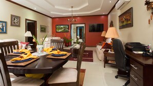 A dining area with a wooden table set for a meal, a sofa, and a desk with a computer.