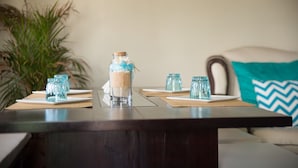 A dining table with a glass jar centerpiece, clear glasses, and a potted plant. - Apartment in Hellshire near Beach (Hellshire)