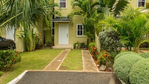 A two-story house with a front yard, a driveway, and a car parked on the left.