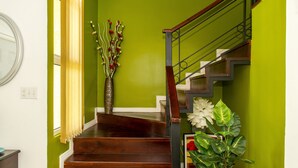A staircase with wooden steps and a metal railing, leading to a landing with a vase of flowers.