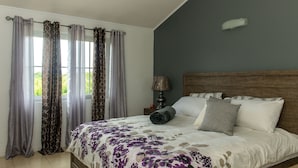A bedroom with a bed, curtains, a nightstand, and a lamp.