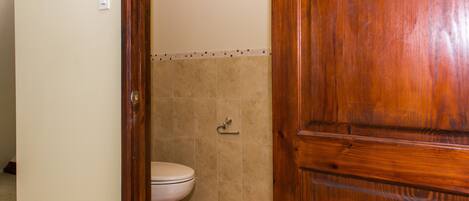 Une salle de bain avec des toilettes, une porte en bois et des murs carrelés.