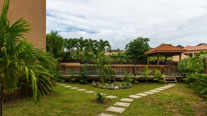 A well-maintained garden with a stone pathway, lush greenery, and a wooden fence.