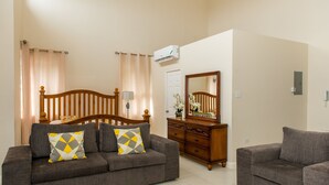 A living room with a sofa, a wooden headboard, a dresser, and a mirror. - City Ridge Luxury Penthouse (Kingston)
