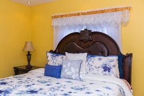 A bed with floral bedding, a wooden headboard, and a nightstand with a lamp. - Kingston Luxury Family Retreat (Kingston)