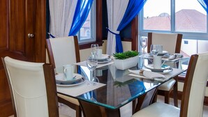 Een eettafel gedekt voor vier personen, met witte borden, glazen en een middelpunt.