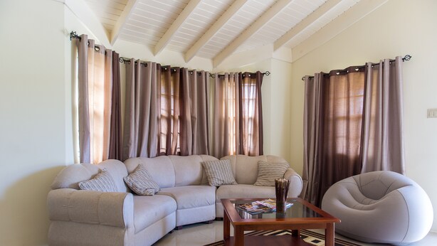 A living room with a sectional sofa, a round bean bag, a coffee table, and a patterned rug. - Ocho Rios Beach House at Dax Hall (Ocho Rios)