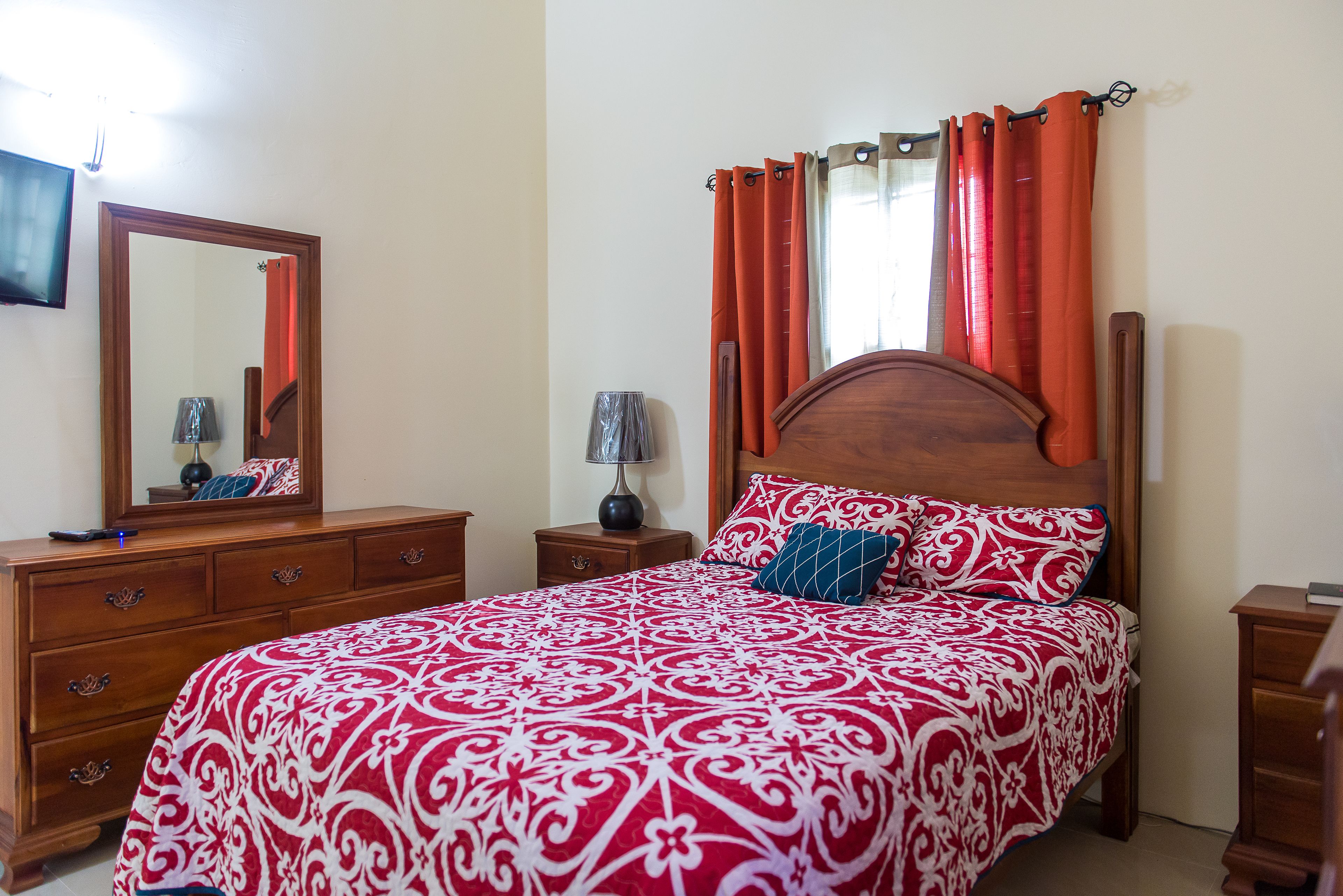 A neatly made bed with a patterned bedspread, a wooden headboard, and matching pillows.