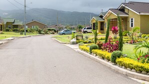 A residential street with houses, a car, and a well-maintained garden. - Ocho Rios Beach House at Dax Hall (Ocho Rios)
