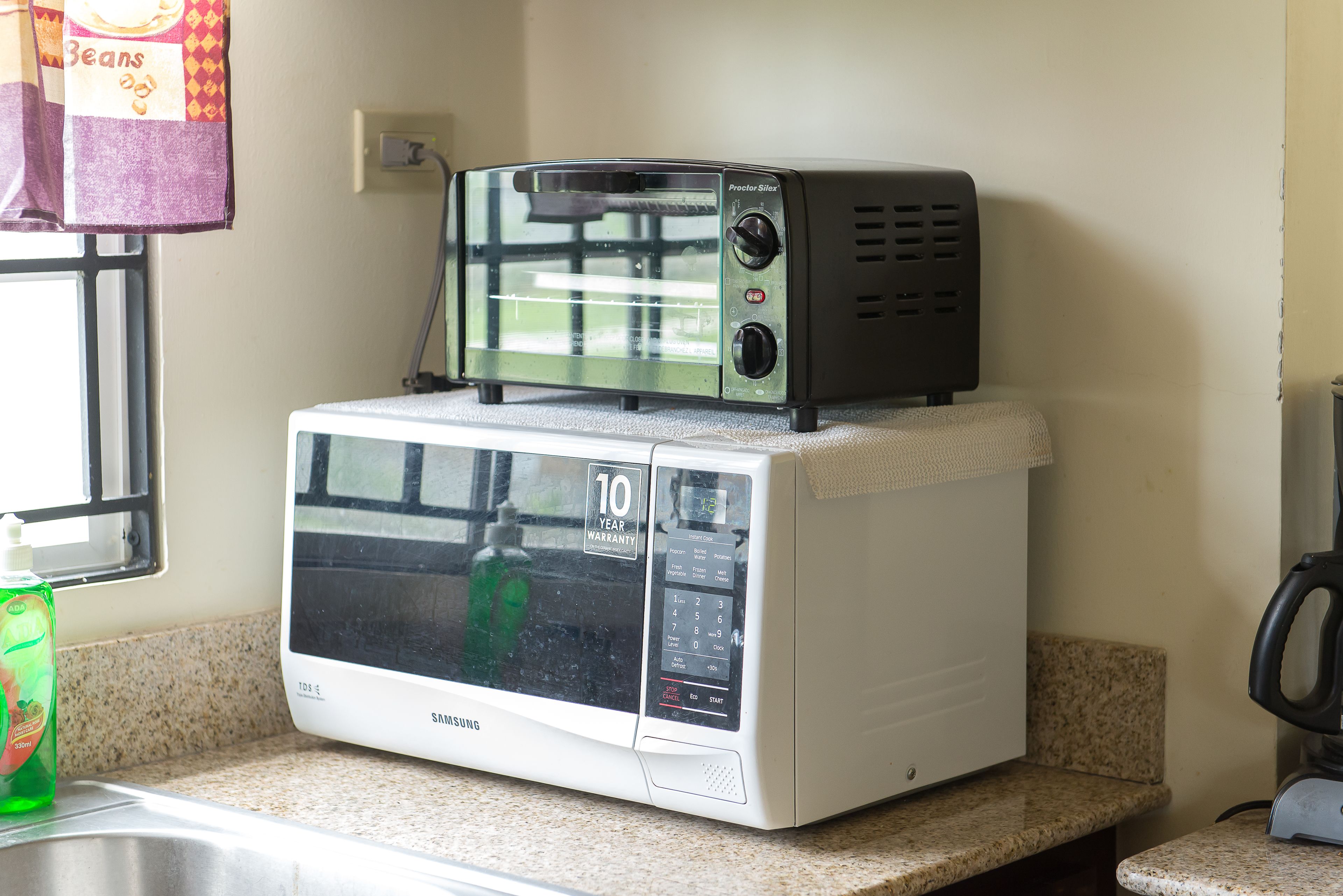 A microwave oven with a 10-year warranty label on the door, placed on a kitchen counter.