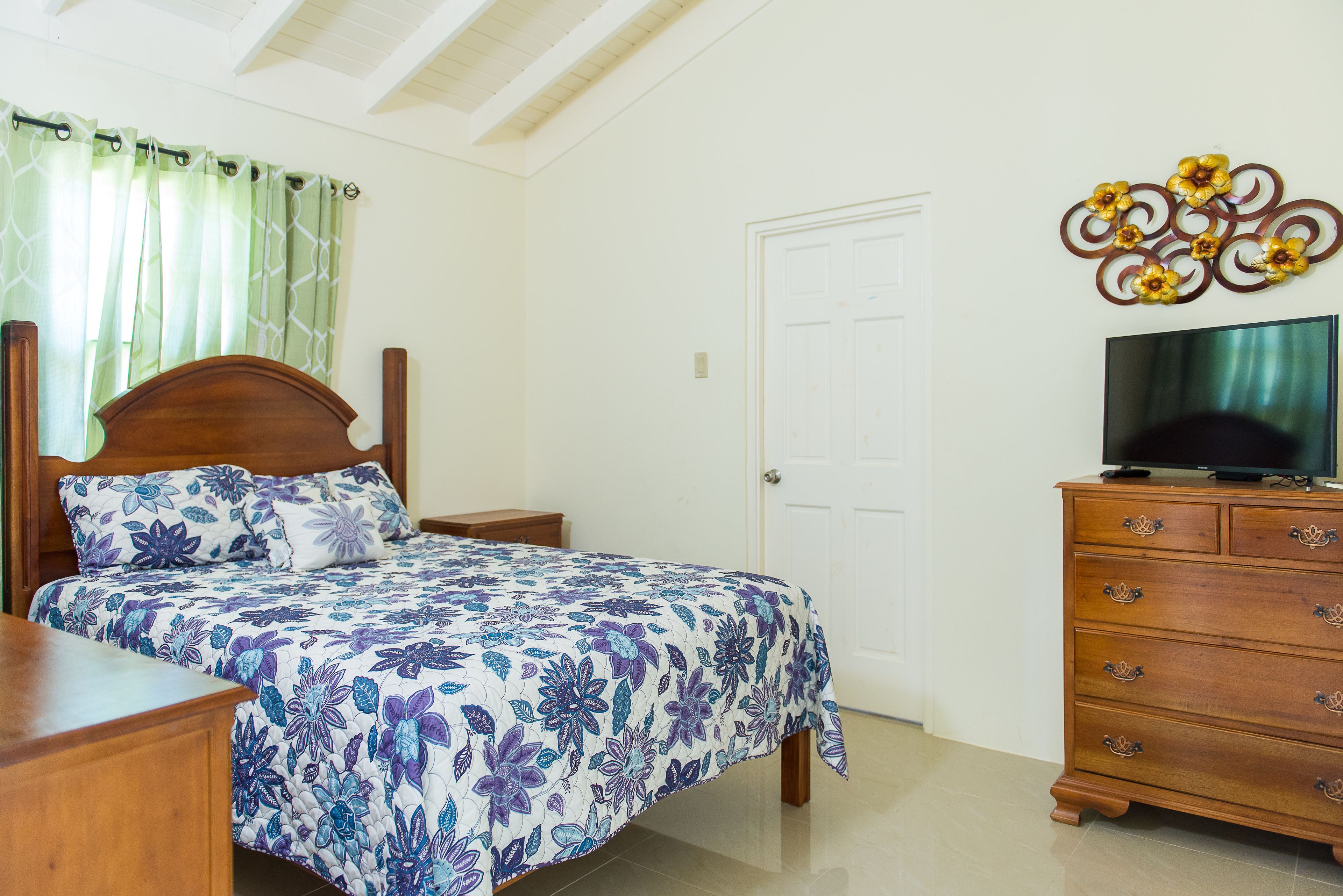 Un dormitorio con cama, cómoda de madera, televisor y un adorno en la pared.