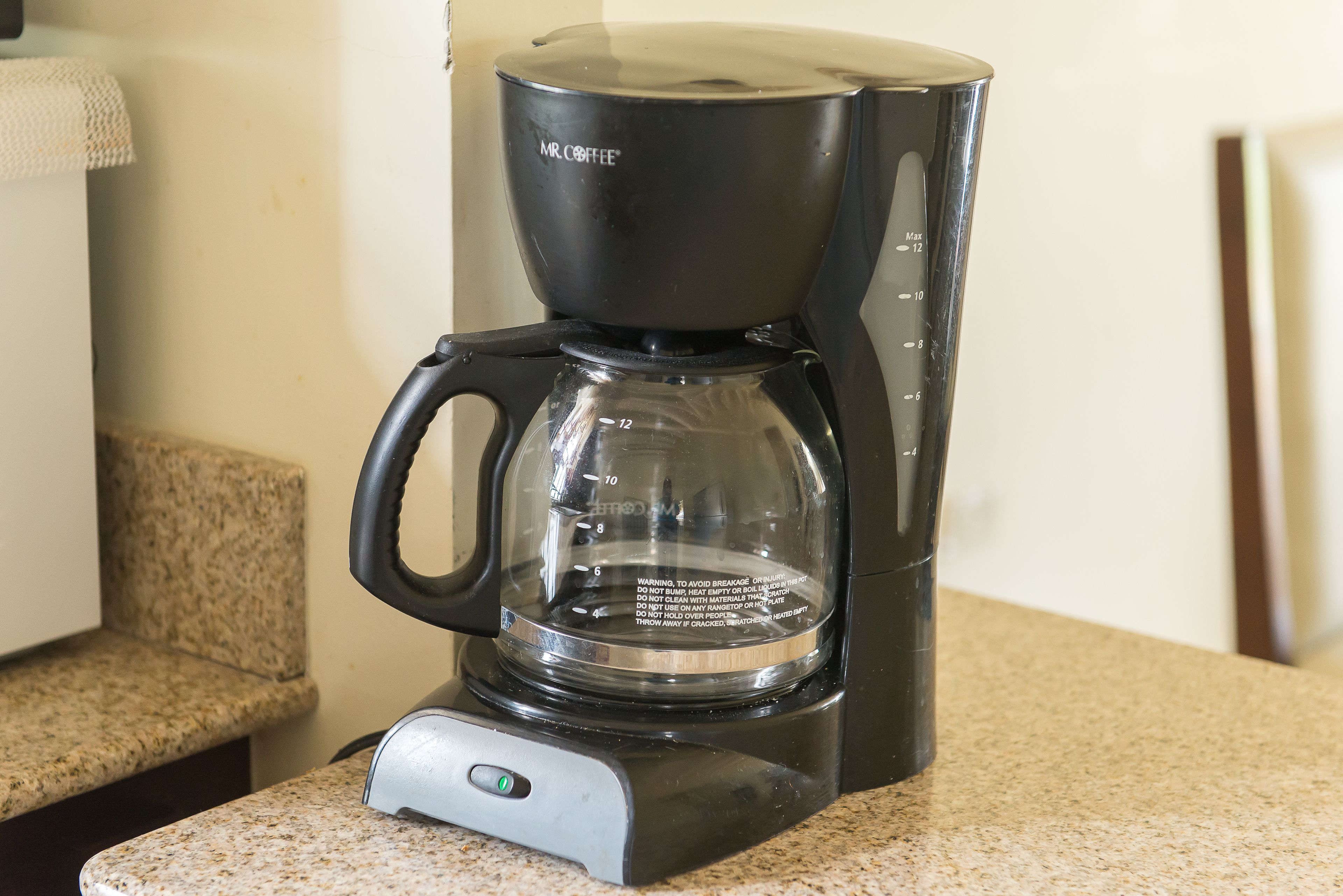 A black Mr. Coffee coffee maker on a granite countertop.