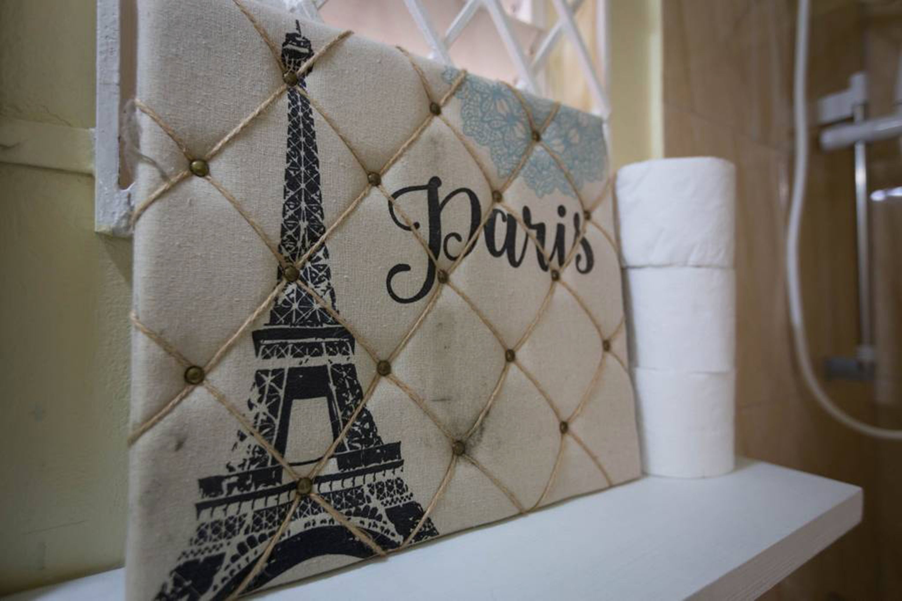 Un baño con un perchero que sostiene un adorno con la Torre Eiffel y la palabra "Paris".