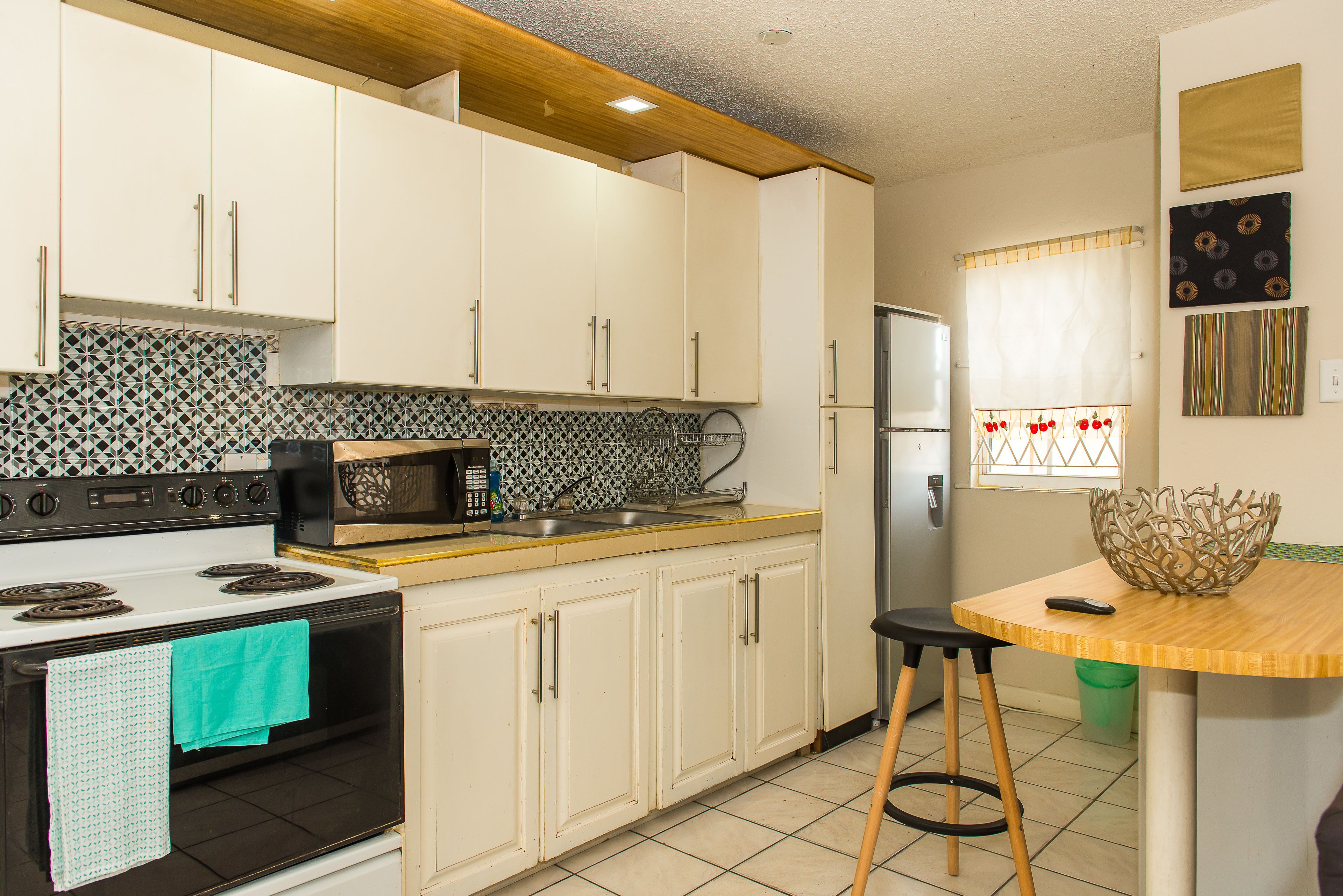 A kitchen with white cabinets, a black stove, a microwave, and a refrigerator.