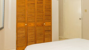 Een slaapkamer met een houten kast, een witte deur en een bed.