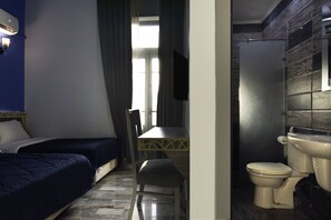 Ein Hotelzimmer mit Bett, Schreibtisch und einem Badezimmer mit Toilette und Waschbecken.