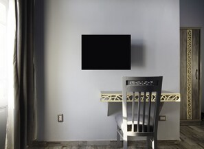 Relax in a stylish space with a flat-screen TV, desk, and comfortable chair.