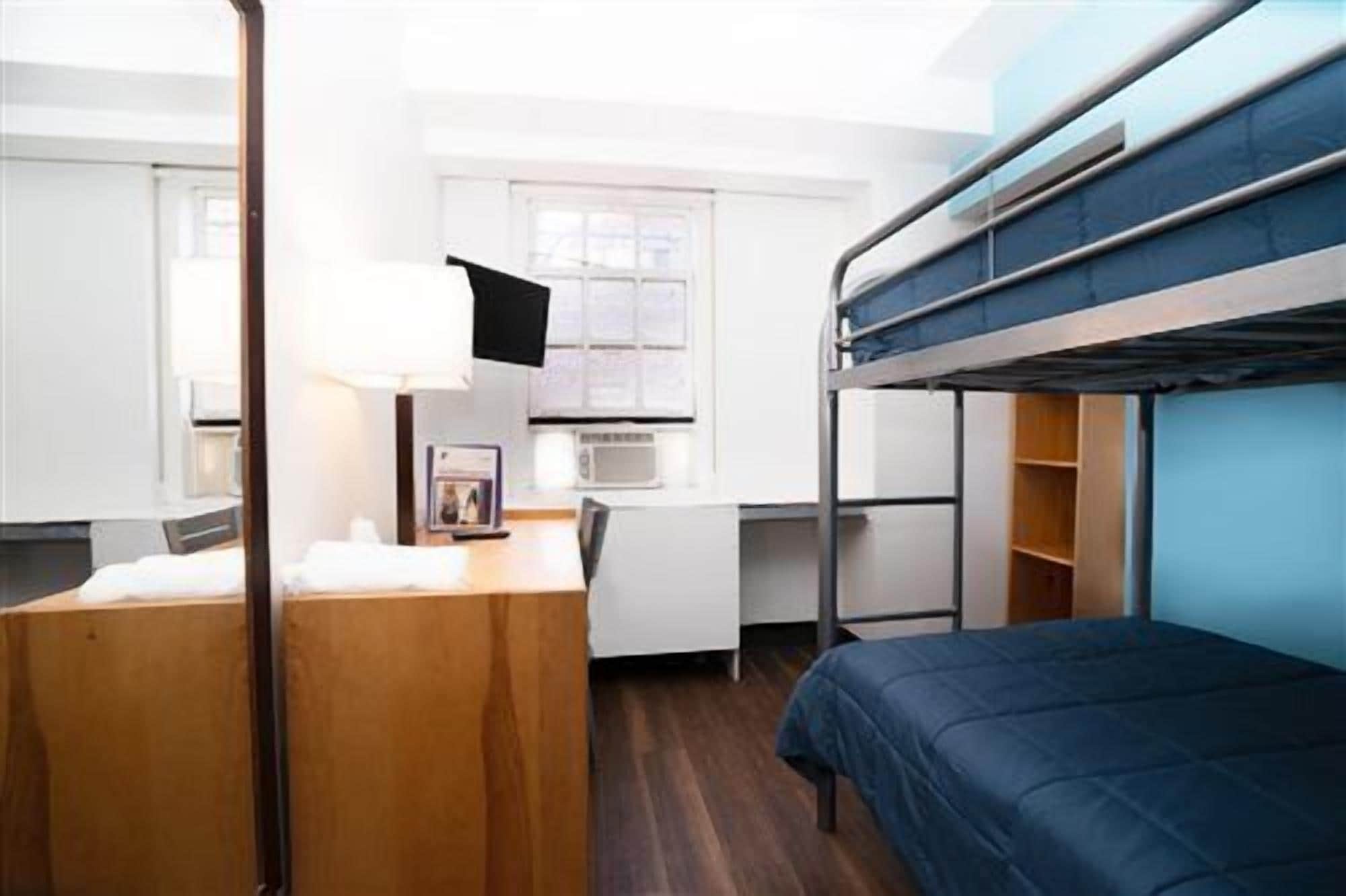 Une chambre avec un lit superposé, un bureau, une lampe et une fenêtre.