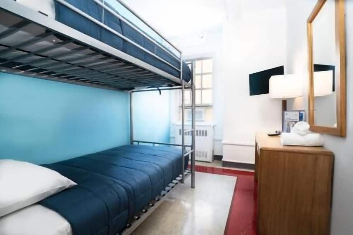 A bunk bed room with a desk and mirror, a window, and a red carpet.