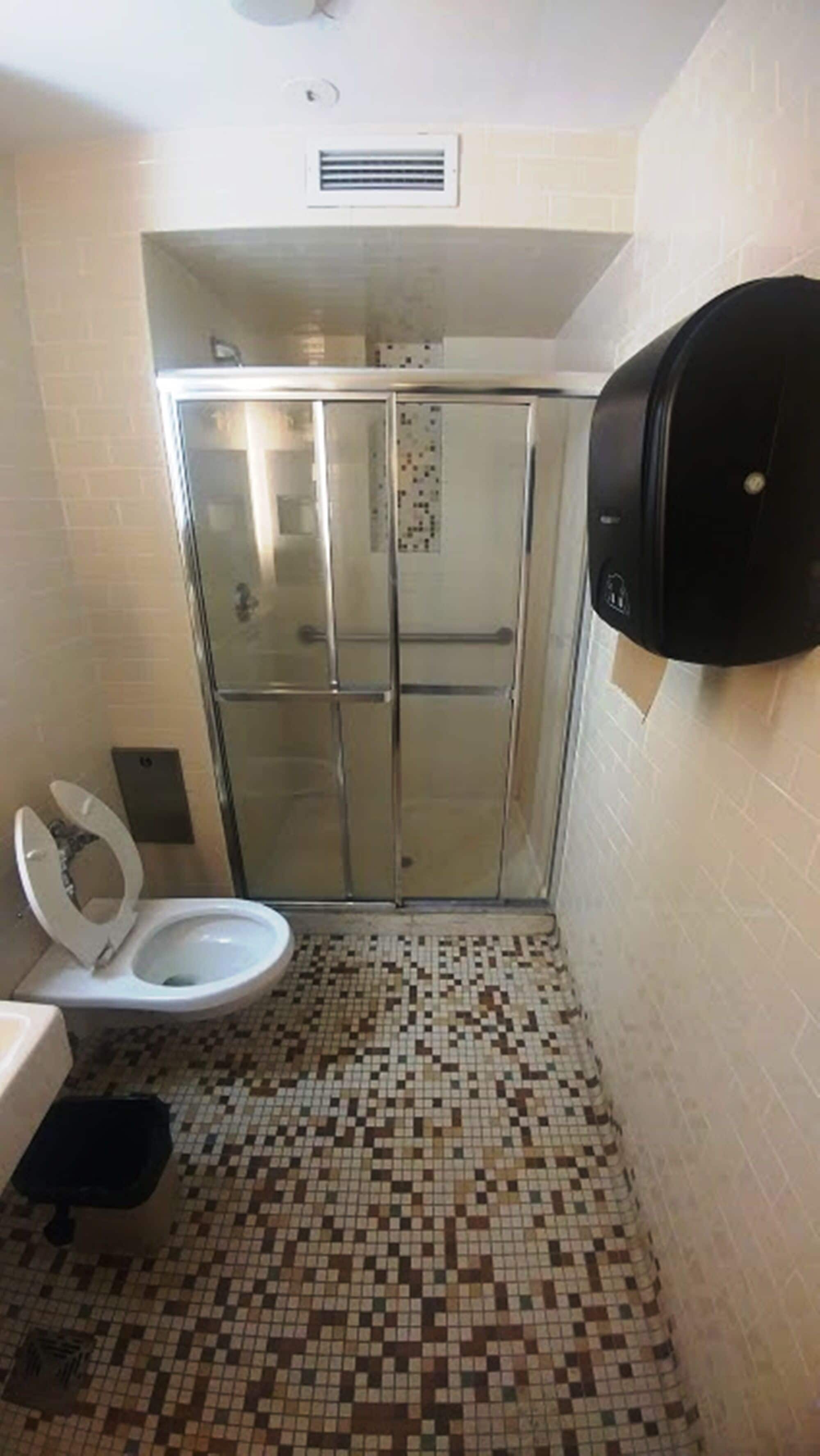 Ein Badezimmer mit Toilette, Duschkabine und einem Handtrockner.