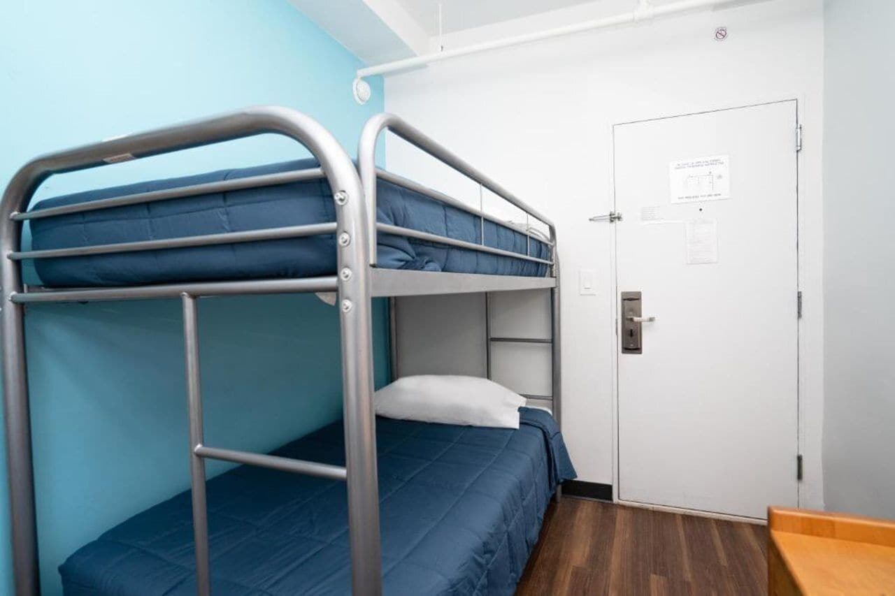 Una camera con un letto a castello, una porta e una piccola panca di legno.