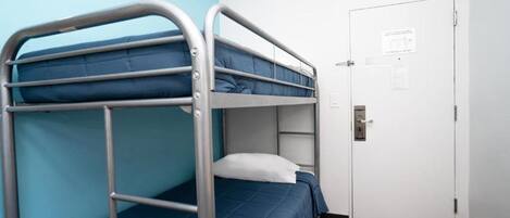 Una camera con un letto a castello, una porta e una piccola panca di legno.