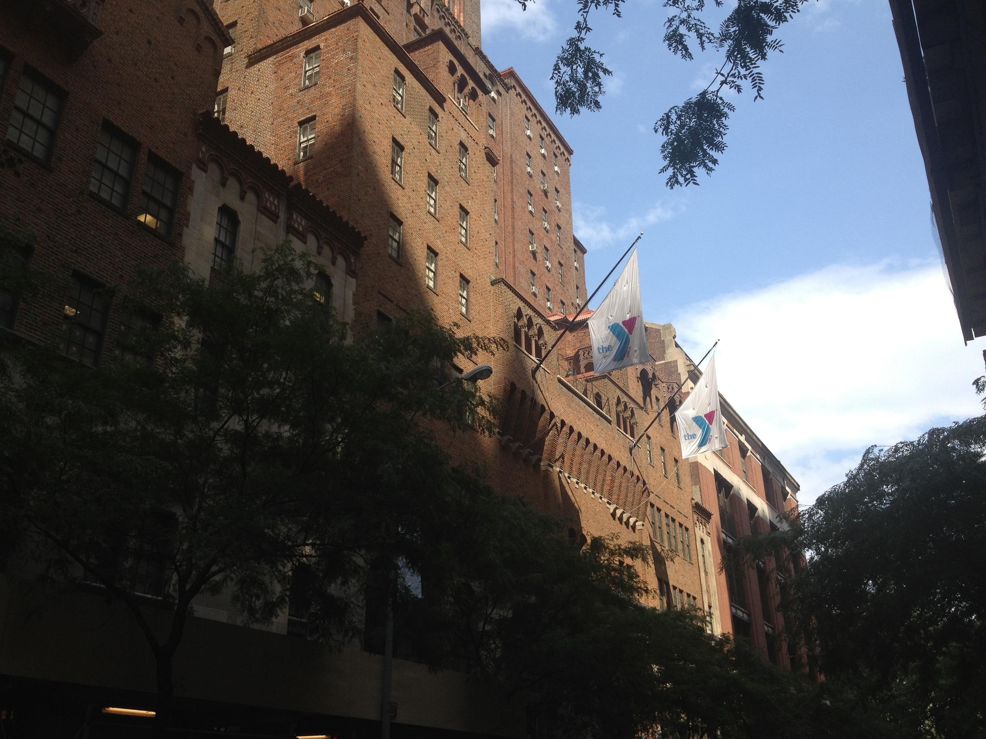 A large brick building with multiple windows and flags.