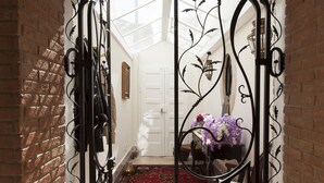 Un arco de entrada con intrincados detalles de metal, que conduce a una habitación con una alfombra estampada y un jarrón de flores.