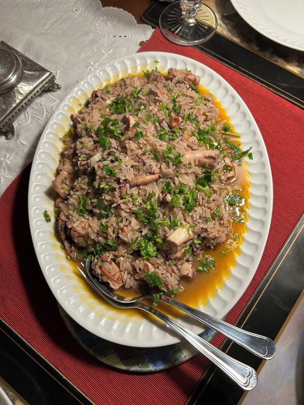 A plate of rice with meat and herbs, accompanied by a spoon and a glass. - Villa Estefânia (Sintra)