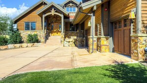 A large, multi-story log cabin with a stone foundation, a central staircase, and a front porch. - Managed by Park City Lodging-Private Home with Stunning Deer Valley Resort Views (Park City)