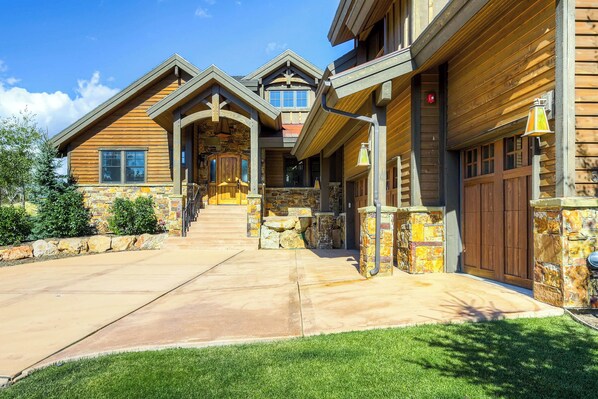 A large, multi-story log cabin with a stone foundation, a central staircase, and a front porch.