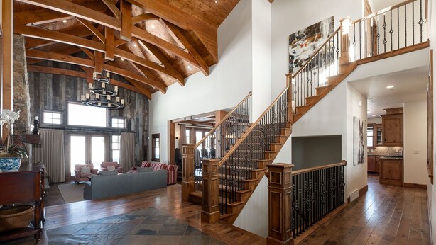 A spacious living area with a wooden staircase, large windows, and a high ceiling. - Managed by Park City Lodging-Private Home with Stunning Deer Valley Resort Views (Park City)