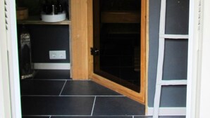 A narrow hallway with a wooden door, shelves with various items, and a ladder against the wall. - B&B de Valkenhorst (Lelystad)