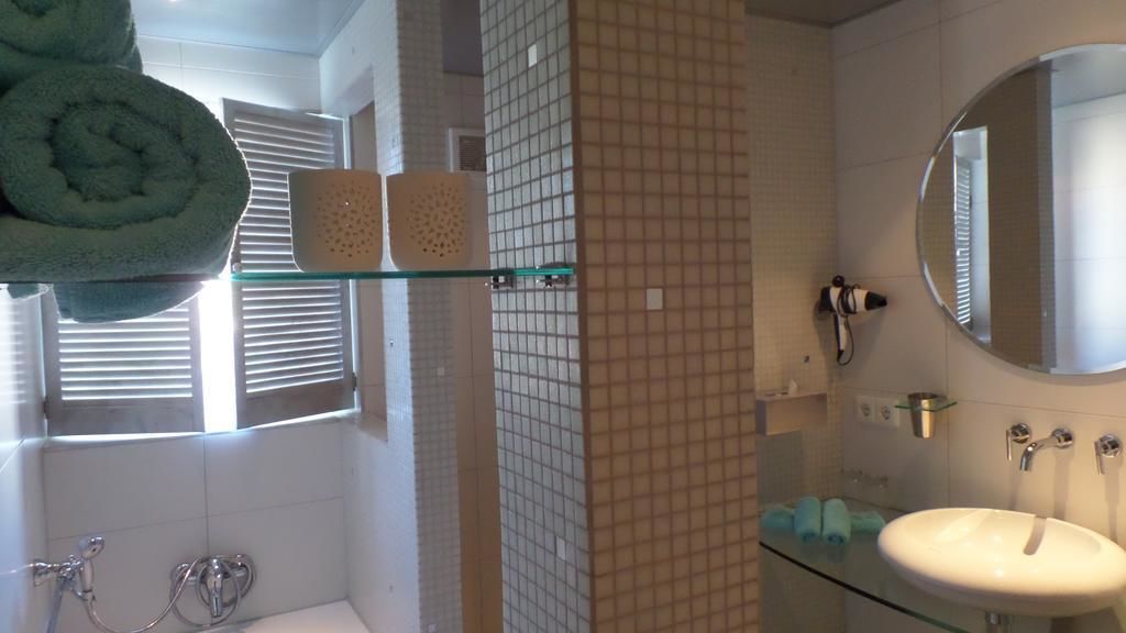 Ein Badezimmer mit Duschkabine aus Glas, Waschbecken in Weiß, Spiegel und Handtuchhalter mit Handtüchern.
