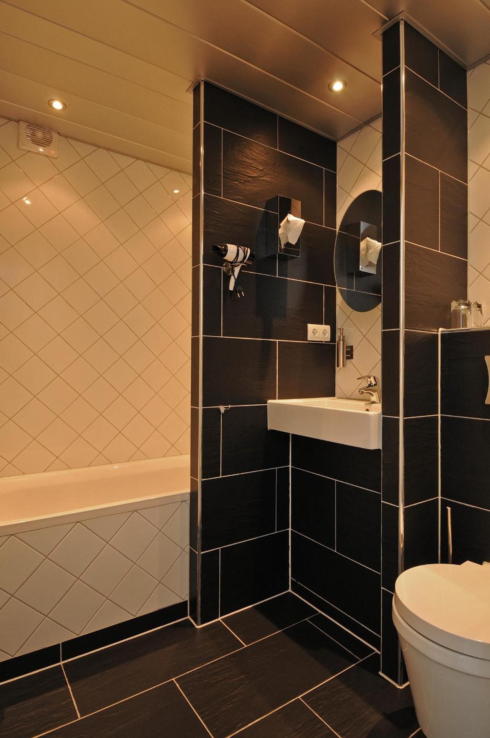 A modern bathroom with a white bathtub, a sink, and a toilet.